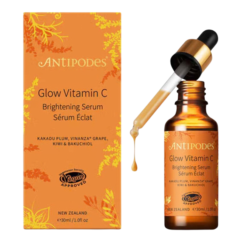 A bottle of Antipodes Glow Vitamin C Brightening Serum with a gold-accented dropper, shown next to its orange packaging box on a white background.