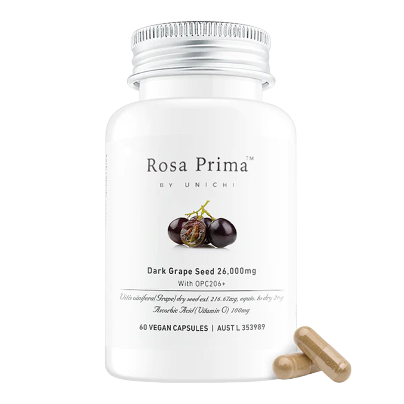 A white bottle of Rosa Prima by Unichi Dark Grape Seed 26,000mg dietary supplement capsules, shown with two beige capsules lying next to it on a clean white background.